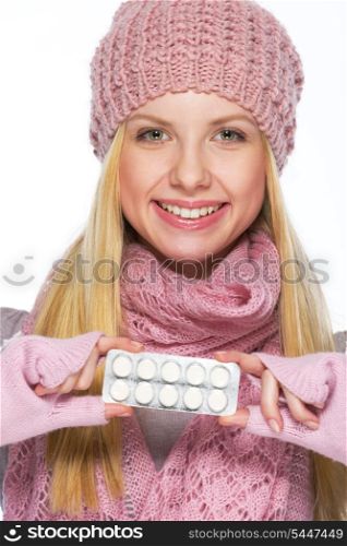 Portrait of smiling teenager girl in winter hat and scarf showing pills pack