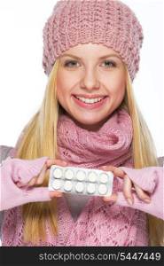 Portrait of smiling teenager girl in winter hat and scarf showing pills pack