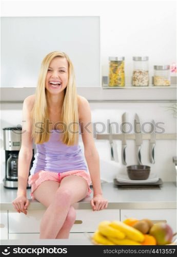 Portrait of smiling teenager girl sitting in modern kitchen
