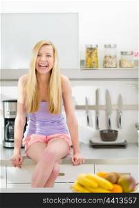 Portrait of smiling teenager girl sitting in modern kitchen