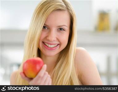 Portrait of smiling teenager girl with apple in kitchen