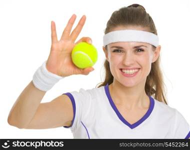 Portrait of smiling tennis player showing tennis ball