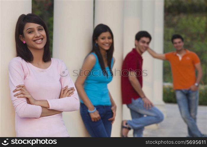 Portrait of smiling woman and friends leaning on columns outdoors