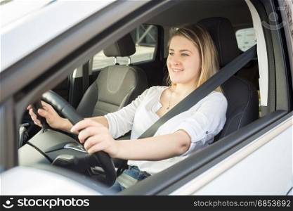 Portrait of smiling woman driving car and looking at camera