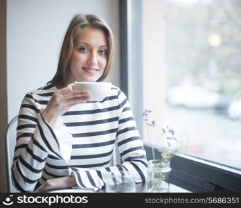 Portrait of smiling woman having coffee at cafe table