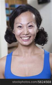 Portrait of smiling woman in a yoga studio, head and shoulders