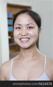 Portrait of smiling woman in a yoga studio, head and shoulders