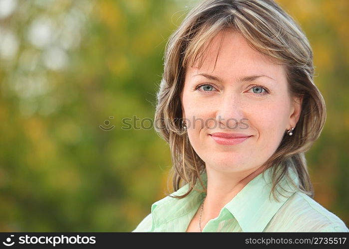 portrait of smiling woman in early fall park. she is looking at camera.