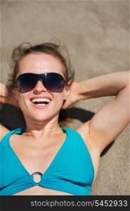 Portrait of smiling woman laying on sand beach