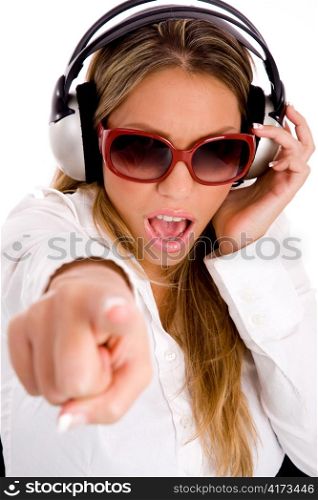 portrait of smiling woman listening music and pointing at camera on an isolated white background