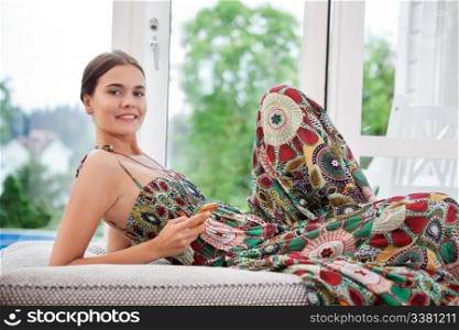 Portrait of smiling woman on bed holding cell phone