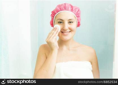 Portrait of smiling woman using face cream after having shower