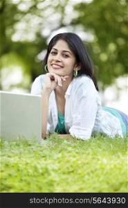 Portrait of smiling woman using laptop while lying on grass