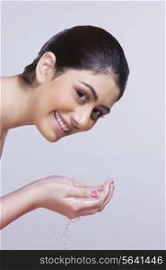 Portrait of smiling woman washing face against gray background