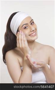 Portrait of smiling woman washing face with soap sud against white background