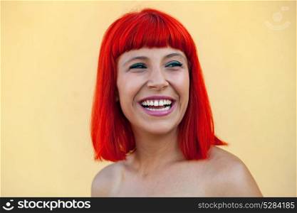 Portrait of smiling woman with red hair on a yellow background