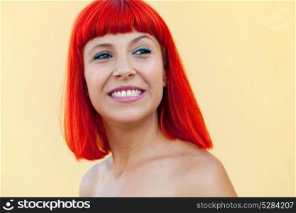 Portrait of smiling woman with red hair on a yellow background