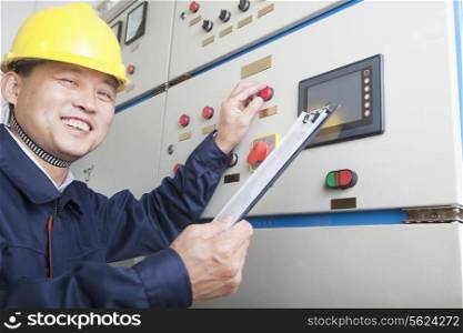 Portrait of smiling worker holding clipboard and checking controls in a gas plant, Beijing, China