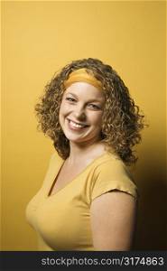 Portrait of smiling young adult Caucasian woman on yellow background.