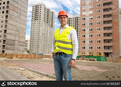 Portrait of smiling young architect standing at buildings under construction