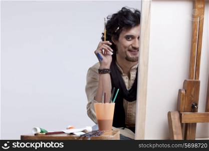 Portrait of smiling young artist with paintbrush