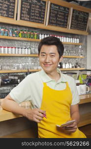 Portrait of smiling young barista with a pad and pen, coffee shop, Beijing