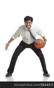 Portrait of smiling young businessman playing basketball