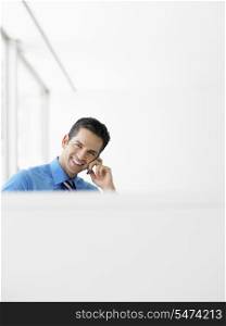 Portrait of smiling young businessman using cell phone at office