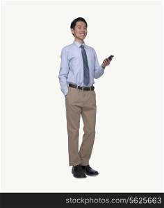Portrait of smiling young businessman using his phone, full length, studio shot