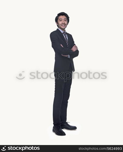 Portrait of smiling young businessman with arms crossed, full length, studio shot