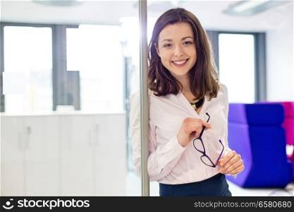 Portrait of smiling young businesswoman holding eyeglasses in office