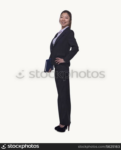 Portrait of smiling young businesswoman holding her personal organizer, full length, studio shot