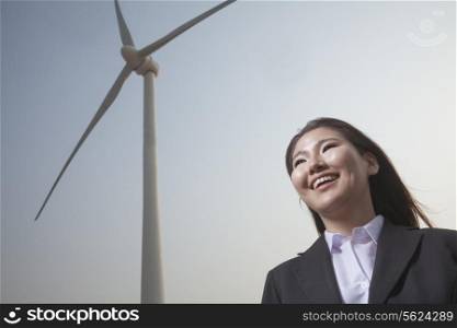 Portrait of smiling young businesswoman standing by a wind turbine