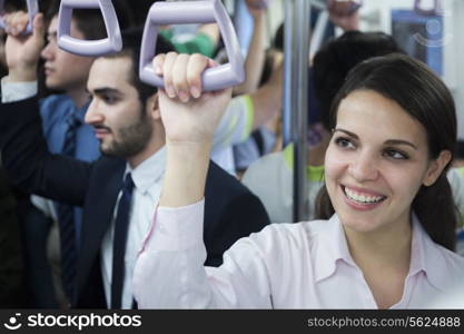 Portrait of smiling young businesswoman standing on the subway, looking away