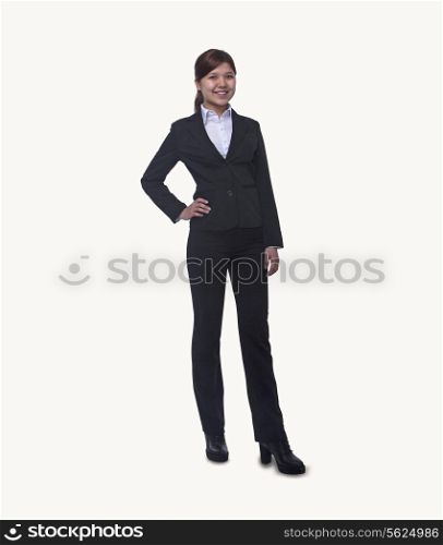 Portrait of smiling young businesswoman with hand on hip looking at camera, full length, studio shot