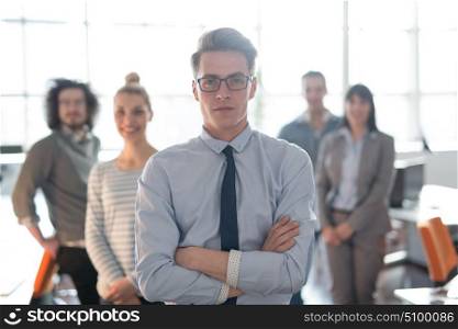 Portrait of smiling young casuall businessman with colleagues in background at the office