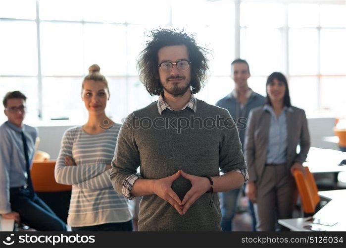 Portrait of smiling young casuall businessman with colleagues in background at the office