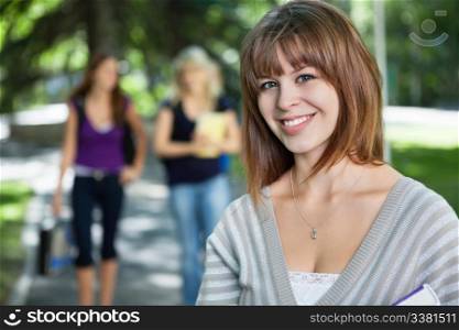 Portrait of smiling young college girl with her friends in background