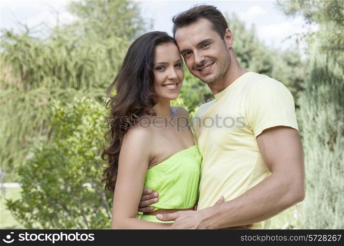 Portrait of smiling young couple embracing in park