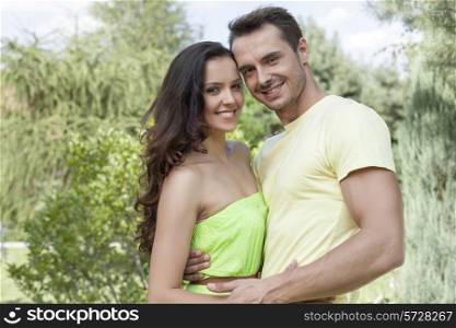 Portrait of smiling young couple embracing in park