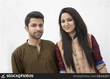 Portrait of smiling young couple wearing traditional clothing from Pakistan, studio shot