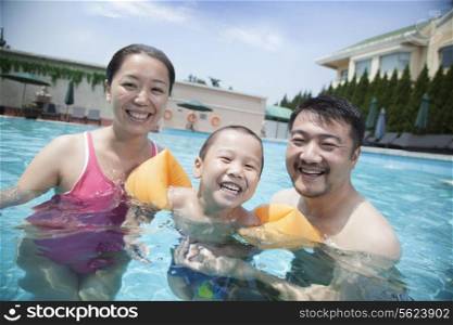 Portrait of smiling young family in the pool on vacation