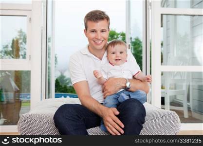 Portrait of smiling young father with child sitting on couch
