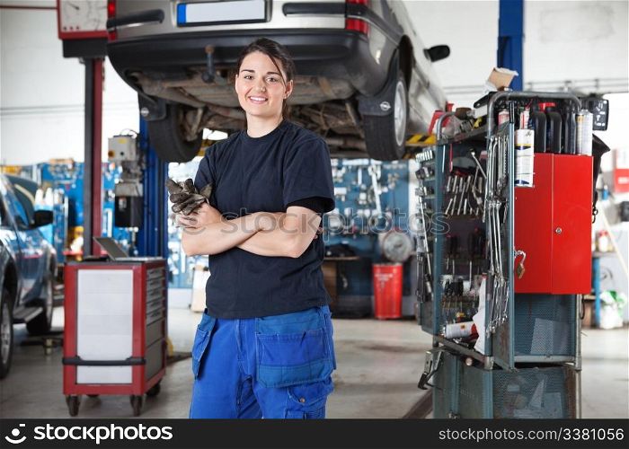 Portrait of smiling young female mechanic with arms crossed in auto repair shop