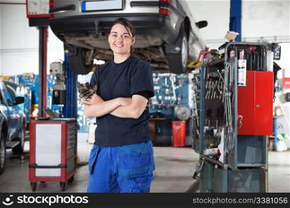 Portrait of smiling young female mechanic with arms crossed in auto repair shop
