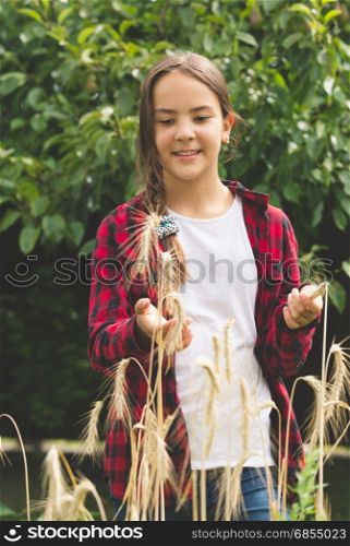 Portrait of smiling young girl in wheat field at sunny day
