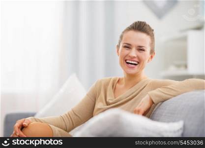 Portrait of smiling young housewife sitting on couch