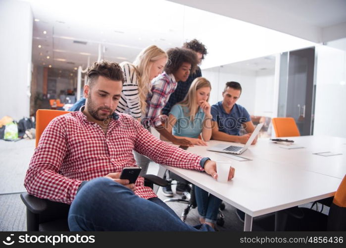 Portrait of smiling young informal businessman with colleagues in background at the office