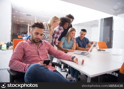 Portrait of smiling young informal businessman with colleagues in background at the office