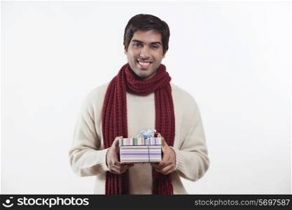 Portrait of smiling young man holding gift box over white background